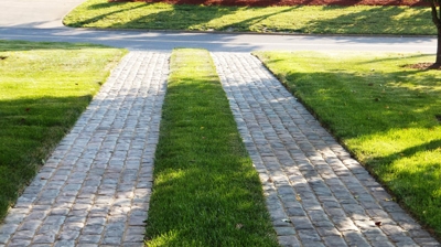 Two rows of gray brick pavers with grass between them. Photo