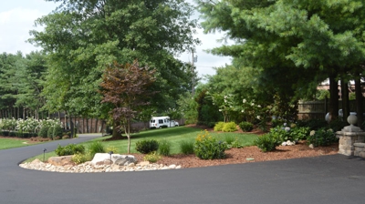 Curved driveway lined with trees and landscaping. Photo