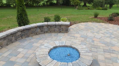 A fire pit with blue stones, surrounded by a patio. Photo