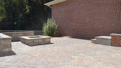 A paved patio with a fire pit and brick walls. Photo