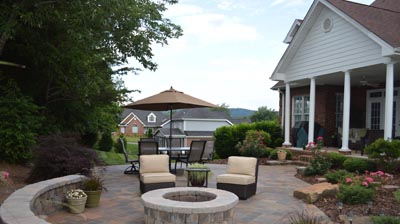 A patio with fire pit, seating, and house in the background. Photo