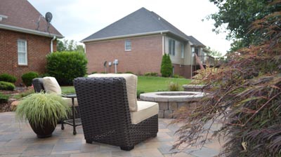 Brown wicker patio furniture sits on a tan stone patio. Photo
