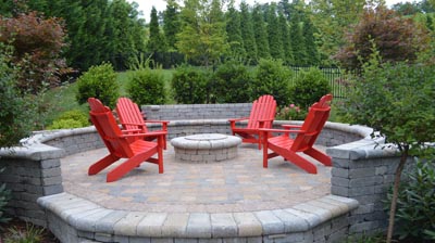 Circular patio with fire pit and red Adirondack chairs. Photo