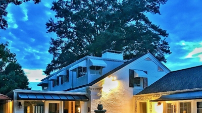 Patio with fountain, house, and trees at twilight. Photo