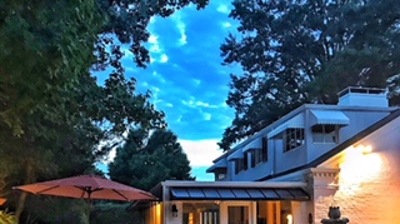 Patio at dusk, with fountain, furniture, and house. Photo