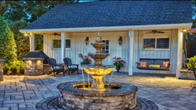 A stone fountain sits in a paved patio. Photo