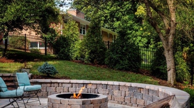 Fire pit with curved stone wall and patio seating. Photo