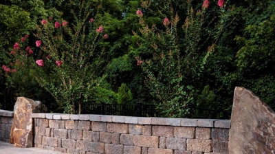 Stone wall, patio, and greenery. Photo