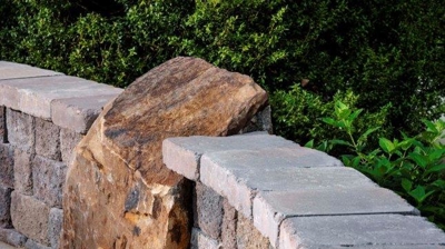 Gray stone wall, large brown rock, patio walkway. Photo