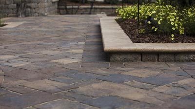 Brown and gray patterned patio with beige flowerbed border. Photo