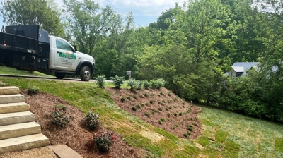 Landscaped hillside with stone steps, bushes, and a truck Photo