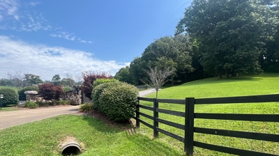 A black wooden fence is alongside the road. Photo