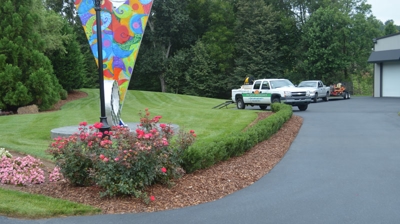 A driveway with landscaping and a colorful sculpture. Photo
