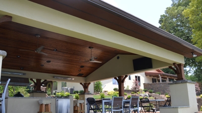 Covered patio with kitchen, dining, and TV. Photo