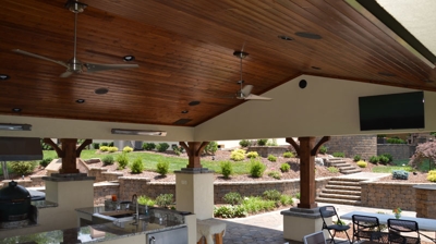 Covered outdoor kitchen with granite, wood ceiling, and yard view. Photo
