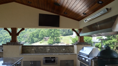 Lakefront outdoor kitchen with granite, grill, and TV. Photo