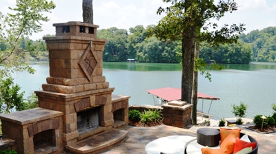 2 piece outdoor sectional couch in front of a stone fireplace kit next to a river Photo