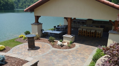 stone staircase leading to a kitchen deck with patio furniture next to a river. Photo