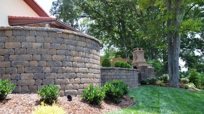 grass and garden next to a curved stone wall in the backyard Photo