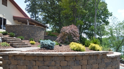 curved stone wall next to stone steps leading to the back of a house. Photo
