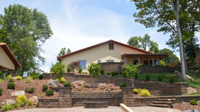 Stone walls, small stone fire pit, dyed brown mulch and grass surround stone steps leading back to the house. Photo