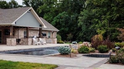 House with stone columns, stone pathway, a pool and patio. Photo