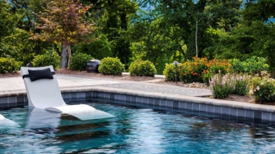 Swimming pool in the patio area next to bushes and trees Photo