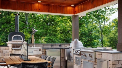 Outdoor kitchen area with oven, grill and dining table. Photo