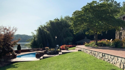 backyard with swimming pool, stone steps, stone walls and trees Photo