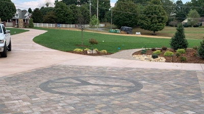 Paved driveway with a circular peace sign design and gray & beige pavers Photo