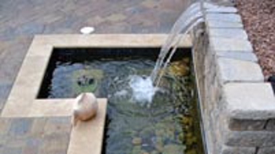 stone wall with waterfall into a small pond in a backyard Photo