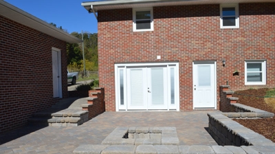 Brick house with a patio, fire pit, and retaining walls Photo