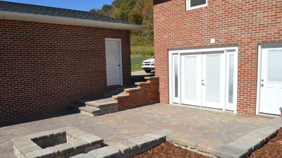 Brick walls enclose a paved patio with a fire pit and steps Photo