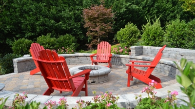 Circular patio with fire pit and red Adirondack chairs Photo