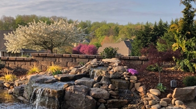 waterfall into small pond with stones and plants in mulch Photo