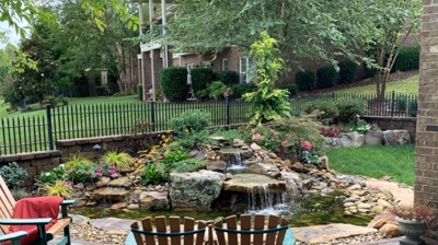 patio chairs in front of a waterfall into a small stone pond Photo