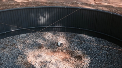 Dark gray pool liner, gravel base, and a white pipe in a hole Photo