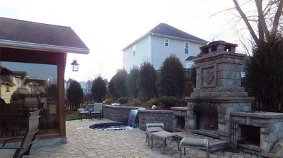 A patio with a stone fireplace and seating area. Photo