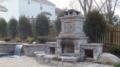Outdoor stone fireplace, patio, seating and water feature. Photo